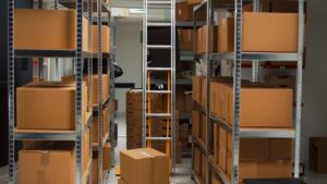 empty-office-space-warehouse-with-carton-boxes-desk-with-laptop-retail-store-products-working-inventory-stock-logistics-storage-room-with-stacks-merchandise-small-business Large