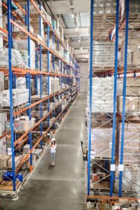 large-warehouse-woman-white-protective-helmet-with-tablet-standing-large-industrial-warehouse-aisle-high-racks-goods Large